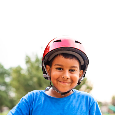 A happy boy wearing a helmet, with a big smile on his face.
