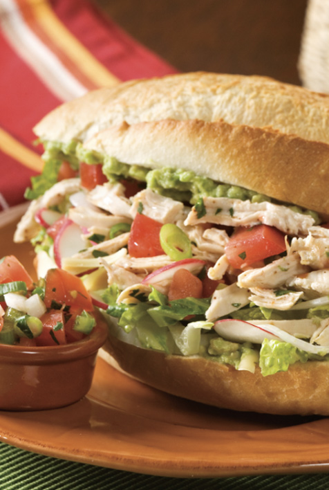 A delicious chicken sandwich with fresh lettuce, juicy tomatoes, and creamy avocado slices.