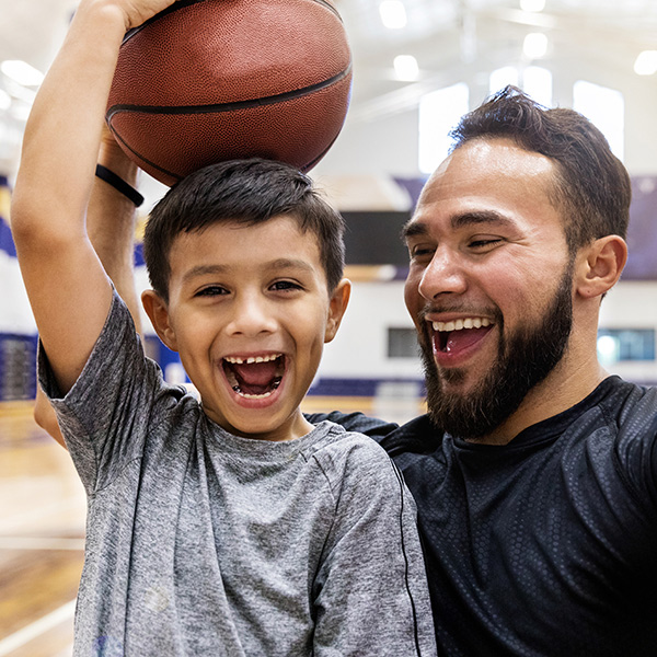 A dad and his son enjoy a game of basketball, encouraging kids to stay active and have fun together.