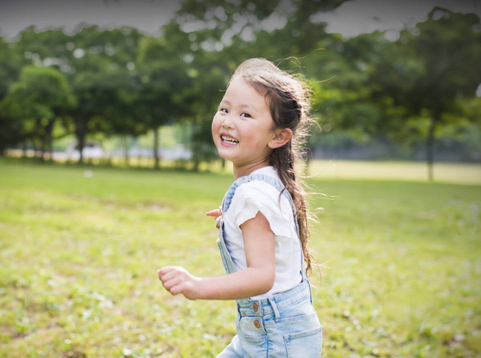 Una niña pequeña corriendo en el césped.