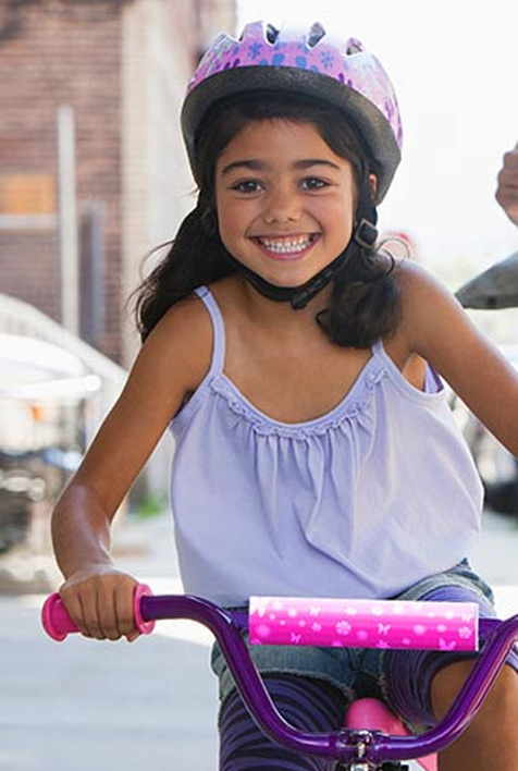 Una niña usando casco mientras monta su bicicleta.