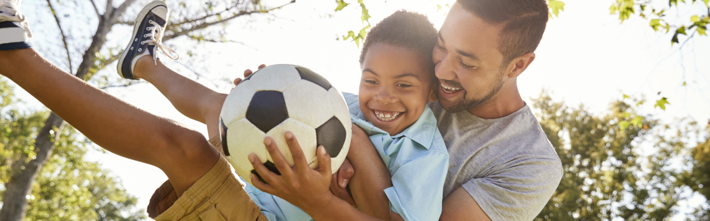 Un hombre y un niño sosteniendo un balón de fútbol.