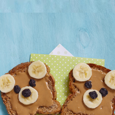 Dos rebanadas de pan tostado con mantequilla de maní y plátano en rodajas, una opción de desayuno deliciosa y nutritiva.