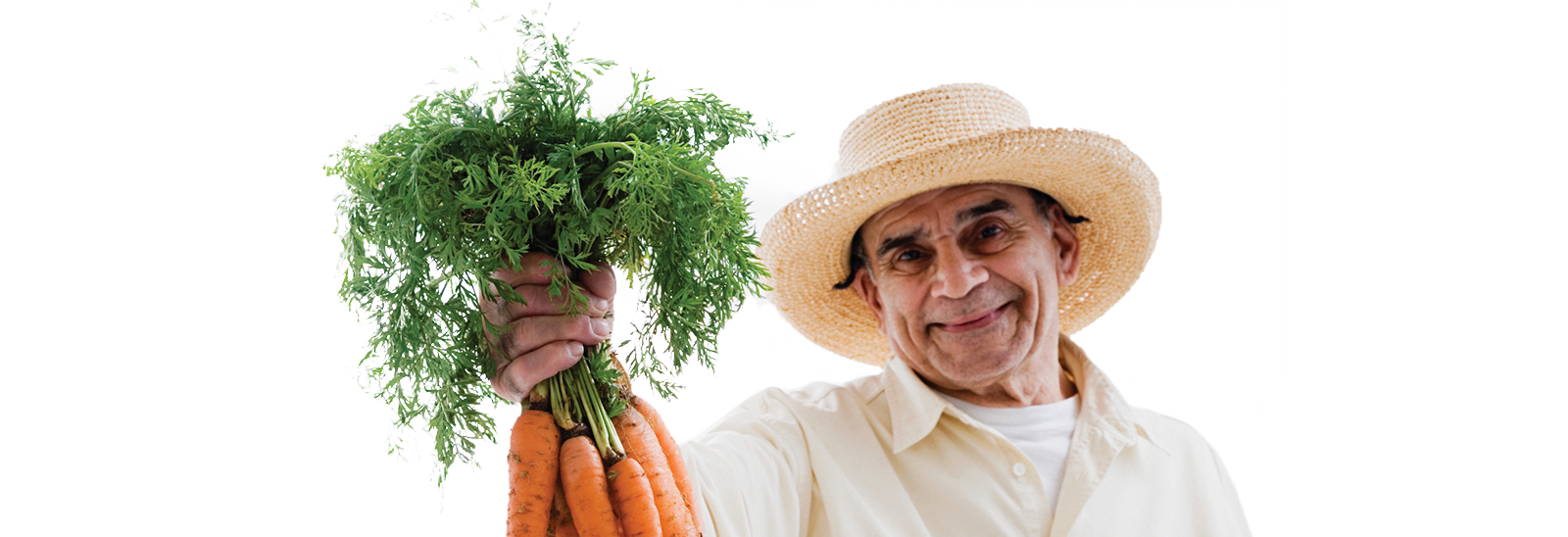 Un señor sonriente sosteniendo un montón de zanahorias frescas 
